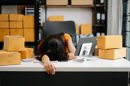 Photo for Startup small business SME, stressed tired Asian woman entrepreneur checking online orders and preparing parcels for shipping - Royalty Free Image