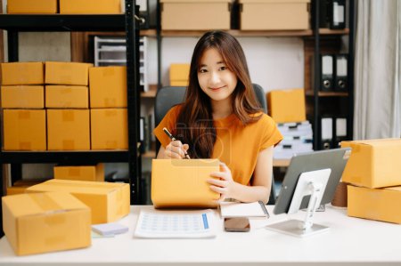 Photo for Startup small business SME, Asian woman entrepreneur checking online orders and preparing parcels for shipping - Royalty Free Image