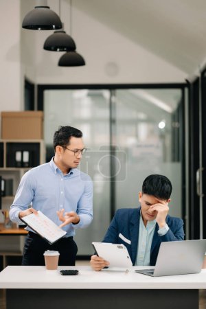 Photo for Furious two Asian businesspeople arguing strongly after making a mistake at work in modern office - Royalty Free Image