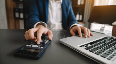 Photo for Close up of businesswoman or accountant hands working to calculate on desk about cost at home office - Royalty Free Image