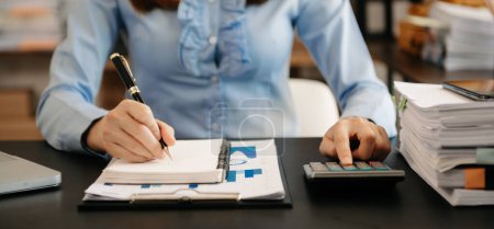 Photo for Businesswoman writing in notepad making calculations - Royalty Free Image