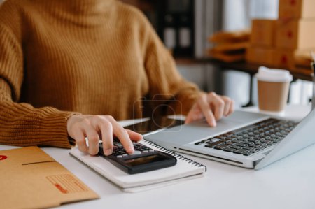 Téléchargez les photos : Femme mains à l'aide d'un ordinateur portable et calculer les chiffres, la finance au bureau de son entreprise achats en ligne à la maison - en image libre de droit
