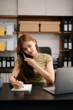 Téléchargez les photos : Business asiatique femme Parler au téléphone tout en étant assis au bureau moderne - en image libre de droit