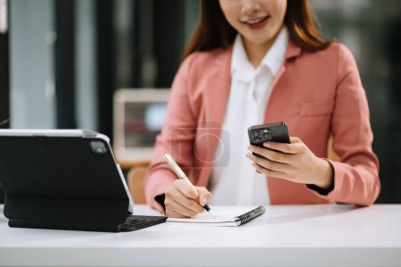 Photo for Businesswoman working with new modern computer and taking notes in office - Royalty Free Image