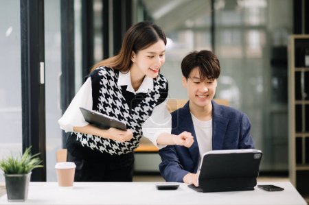 Téléchargez les photos : Homme d'affaires asiatique avec collègue femme utilisant tablette dans la salle de bureau moderne. Travail d'équipe, équipe de marketing financier - en image libre de droit
