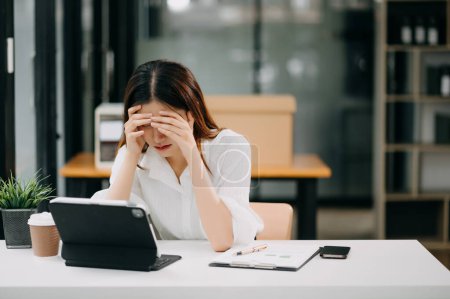 Asiatische Geschäftsfrau gestresst und gelangweilt nach langem Tag im Büro.