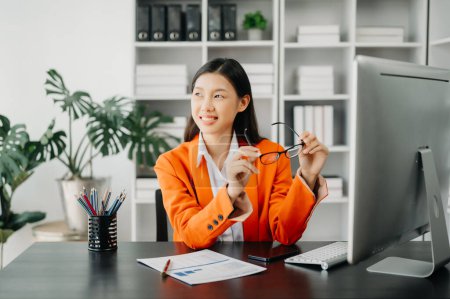 Photo for Attractive Asian female office worker business suit working with computer in modern office - Royalty Free Image