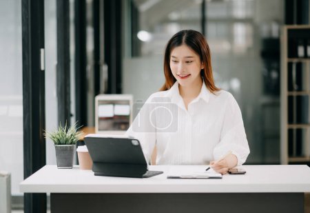 Photo for Successful Asian Businesswoman Analyzing Finance on Tablet Computer at Office Desk tax, report, accounting, statistics, and analytical research concept - Royalty Free Image
