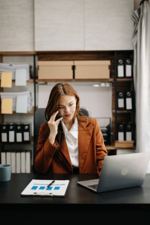 Photo for Happy young Asian woman working in modern office. Businesswoman talking over mobile phone - Royalty Free Image
