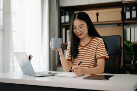 Téléchargez les photos : Asiatique fille bibliothèque assis au bureau à l'aide d'un ordinateur portable pour rechercher une information en ligne - en image libre de droit