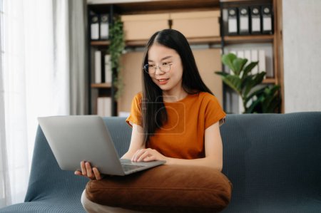 Téléchargez les photos : Asiatique fille bibliothèque assis au bureau à l'aide d'un ordinateur portable pour rechercher une information en ligne - en image libre de droit