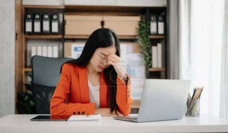 Photo for Asian woman feeling migraine head strain. Overworked businesswoman financier working on laptop in office - Royalty Free Image