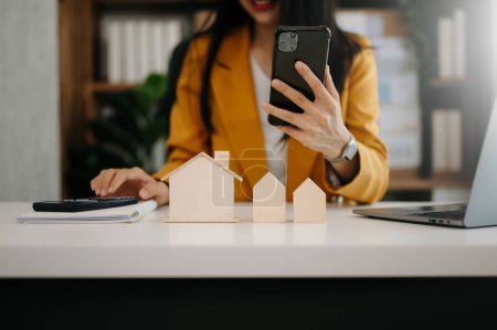 Foto de Agente inmobiliario femenino que trabaja en la inversión sobre el comercio de casa, compra en el escritorio en la oficina con teléfono inteligente - Imagen libre de derechos