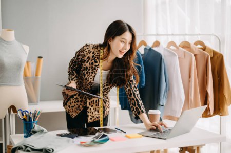 Téléchargez les photos : Créateur de mode prospère. attrayant jeune asiatique femme de travail dans studio comme couturière - en image libre de droit