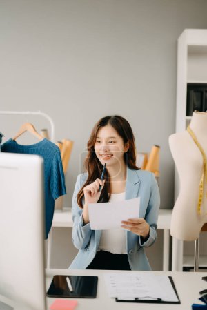 Photo for Successful fashion designer. Attractive young asian woman working in studio as dressmaker - Royalty Free Image