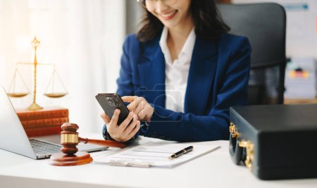 Photo for Justice and law concept. Female judge in a courtroom the gavel, working with smartphone at white table in office - Royalty Free Image