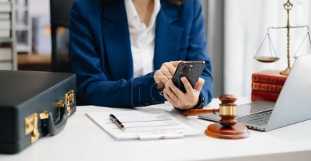 Photo for Justice and law concept. Female judge in a courtroom the gavel, working with smartphone at white table in office - Royalty Free Image