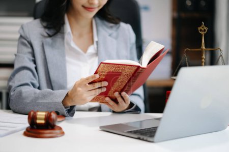 Foto de Una abogada leyendo un libro legal con mazo en la mesa en la oficina. justicia y derecho - Imagen libre de derechos