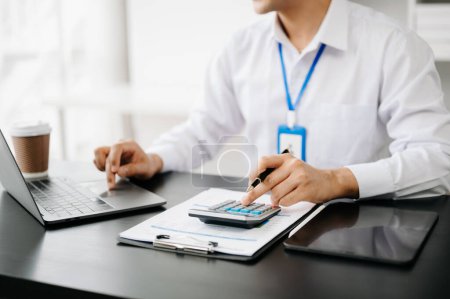 Photo for Close up of businessman or accountant hand typing laptop working to calculate on desk about cost at modern office - Royalty Free Image