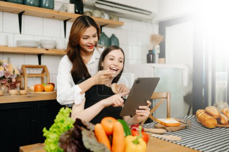 Photo for Image of couple cooking at home. young  women cooking together with in cozy kitchen - Royalty Free Image