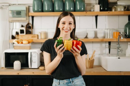 Photo for Beautiful adult woman with bell peppers looking camera on kitchen. healthy food concept - Royalty Free Image
