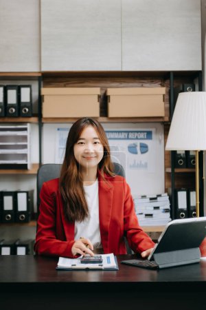 Téléchargez les photos : Confiant belle femme d'affaires asiatique travaillant sur tablette numérique au bureau moderne - en image libre de droit