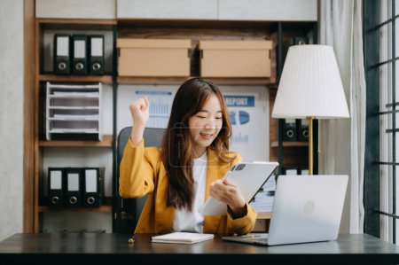 Téléchargez les photos : Femme d'affaires asiatique sont ravis et heureux de célébrer la réalisation avec le travail qu'ils font sur tablette numérique au bureau. - en image libre de droit