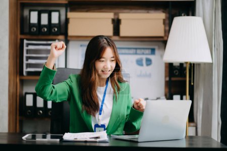 Téléchargez les photos : Femme d'affaires asiatique sont ravis et heureux de célébrer la réalisation avec le travail qu'ils font sur ordinateur portable au bureau. - en image libre de droit