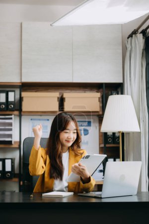 Téléchargez les photos : Femme d'affaires asiatique sont ravis et heureux de célébrer la réalisation avec le travail qu'ils font sur tablette numérique au bureau. - en image libre de droit