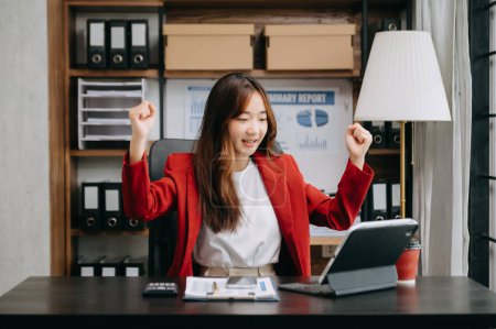 Téléchargez les photos : Femme d'affaires asiatique sont ravis et heureux de célébrer la réalisation avec le travail qu'ils font sur tablette numérique au bureau - en image libre de droit