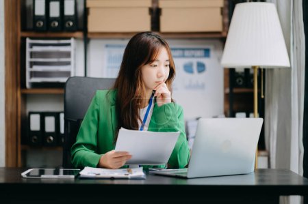 Foto de Experta asiática confiada en negocios atractiva joven sonriente sosteniendo tableta digital en el escritorio en la oficina creativa - Imagen libre de derechos