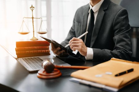 Foto de Concepto de justicia y derecho. Juez masculino en un tribunal el mazo, trabajando con la tableta digital en la mesa blanca - Imagen libre de derechos