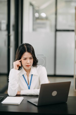 Photo for Frustrated young businesswoman working on a laptop computer sitting at his working place in office - Royalty Free Image