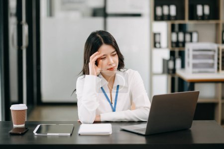 Téléchargez les photos : Frustré jeune femme d'affaires travaillant sur un ordinateur portable assis à son lieu de travail dans le bureau - en image libre de droit