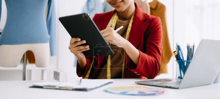 Photo for Calm curly brunette dark skinned woman on desk in modern office of fashion designer and holds tablet - Royalty Free Image