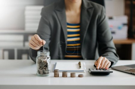 Foto de Mujer de negocios poniendo monedas en vidrio en la oficina - Imagen libre de derechos