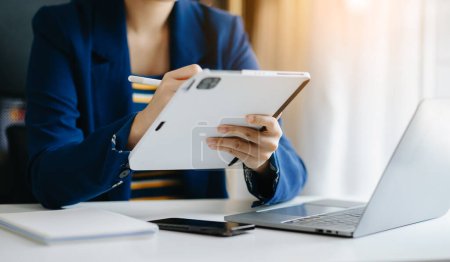 Téléchargez les photos : Femme d'affaires travaillant sur tablette numérique dans le bureau à la table à la lumière du matin - en image libre de droit