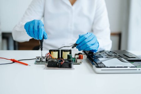 Electronics technician measuring and testing, repair and maintenance concepts, uses a voltage meter to check and upgrade in shop 