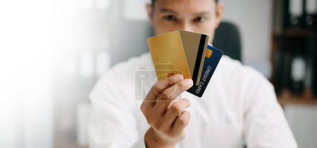 Foto de Deuda financiera, hombre asiático sentado, con tarjeta de crédito, estresado por calcular el gasto de la factura o factura - Imagen libre de derechos