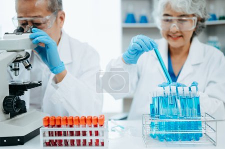 Photo for Senior scientists conducting research investigations in a medical laboratory, a researcher in the foreground is using a microscope in laboratory for medicine. - Royalty Free Image