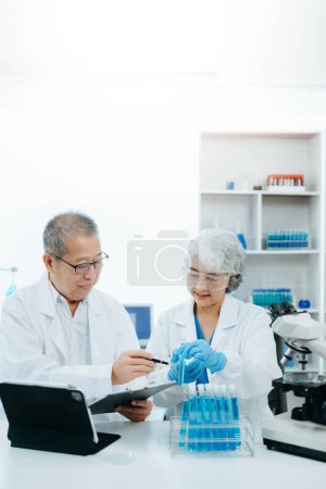 Foto de Dos científicos o técnicos médicos que trabajan, teniendo un debate médico en el laboratorio con la lectura en línea, muestras de prueba y la innovación - Imagen libre de derechos