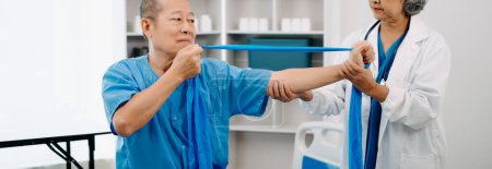 Foto de Fisioterapeuta asiática ayudar anciano paciente estiramiento brazo en hospital - Imagen libre de derechos