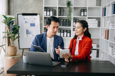 Téléchargez les photos : Homme d'affaires asiatique avec une collègue féminine utilisant un ordinateur portable dans la salle de bureau moderne. Travail d'équipe, équipe de marketing financier - en image libre de droit
