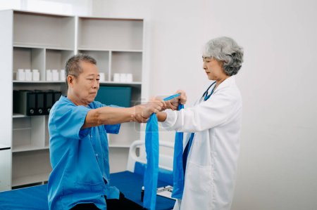 Photo for Asian physiotherapist helping elderly man patient stretching arm in hospital - Royalty Free Image