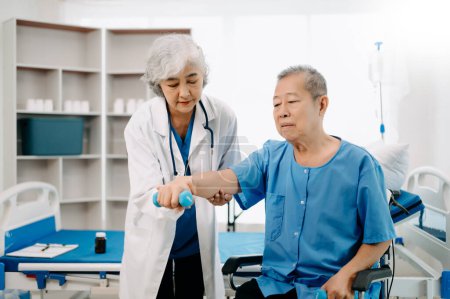 Téléchargez les photos : Asiatique physiothérapeute aider l'homme âgé patient étirement bras à l'hôpital - en image libre de droit