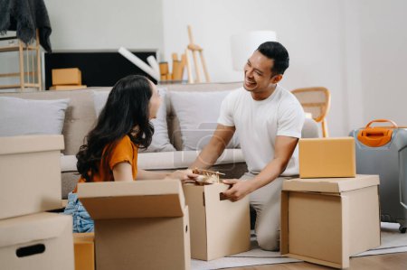 Foto de Pareja joven con grandes cajas mudándose a una casa nueva. Asiático hombre y mujer ayudando a levantar cajas para el nuevo hogar - Imagen libre de derechos
