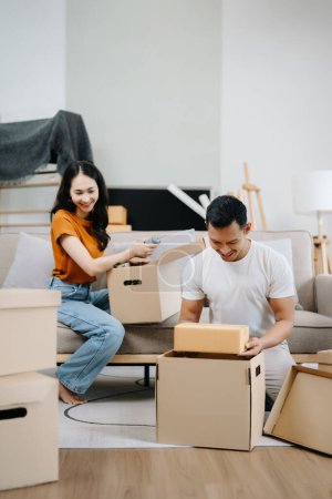 Photo for Happy asian young attractive couple man and woman with big boxes moving into a new house - Royalty Free Image