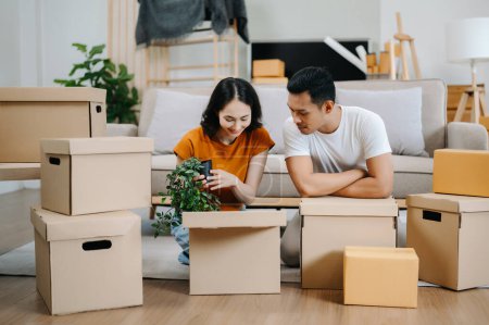 Foto de Pareja joven con grandes cajas mudándose a una casa nueva. Asiático hombre y mujer ayudando a levantar cajas para el nuevo hogar - Imagen libre de derechos
