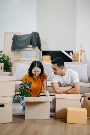 Photo for Young couple with big boxes moving into a new house. Asian man and woman helping to lift boxes for the new home - Royalty Free Image