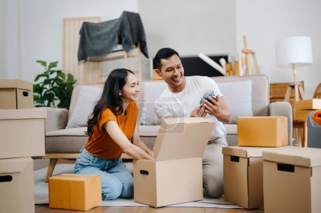 Heureux asiatique jeune attrayant couple homme et femme avec de grandes boîtes de déménagement dans une nouvelle maison